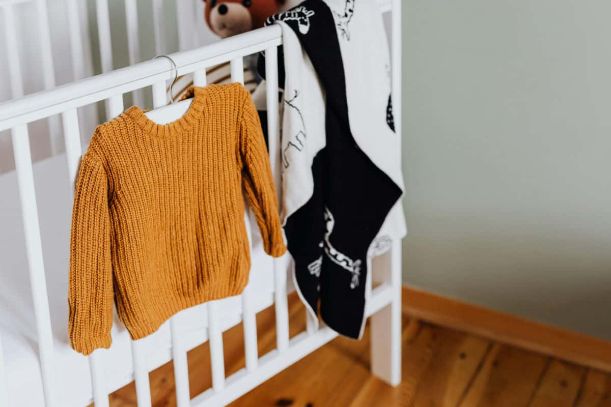 Yellow jumper hanging from a baby's cot