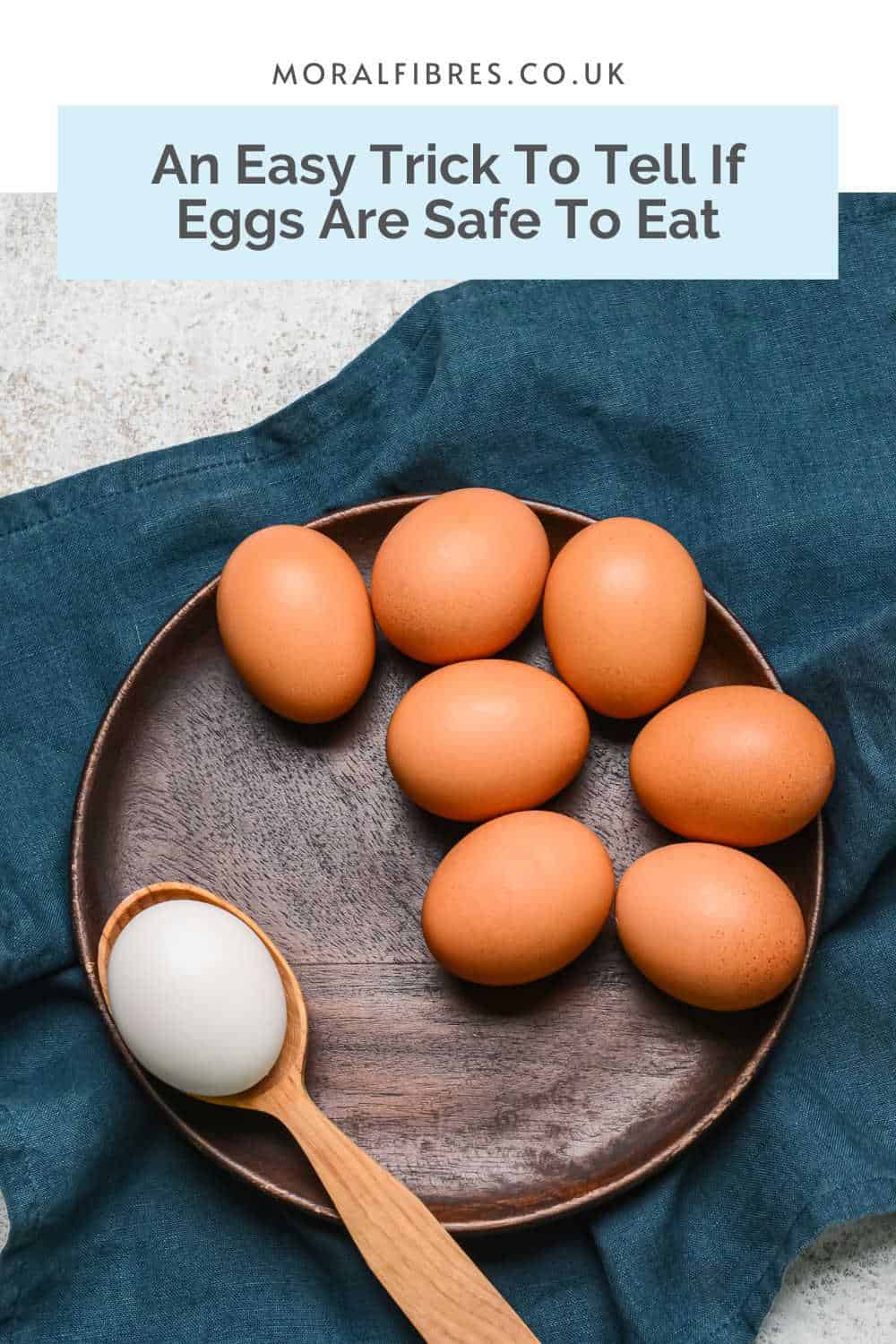 Fresh eggs in a wooden bowl with a blue text box that reads an easy trick to test eggs for freshness.